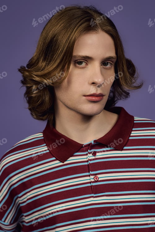 Preview: Young man showcases stylish outfit in modern studio setting with vibrant backdrop