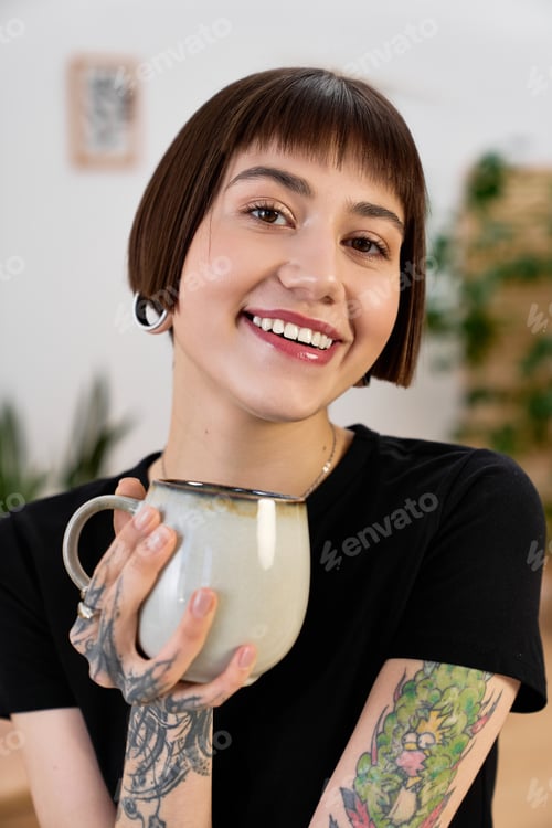 Preview: Joyful young woman enjoys a cozy moment at home with her favorite mug in hand