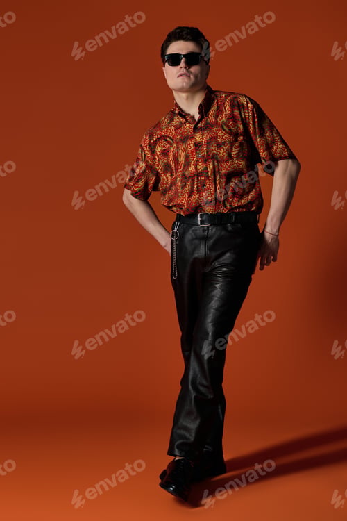 Preview: Elegant young man striking a confident pose against a vibrant orange background