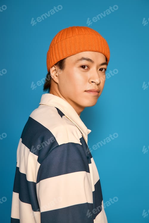 Preview: Stylish asian young man exudes confidence in unique fashion in a studio setting