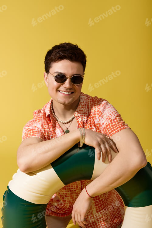 Preview: Stylish young man enjoying summer vibes with a colorful pool float