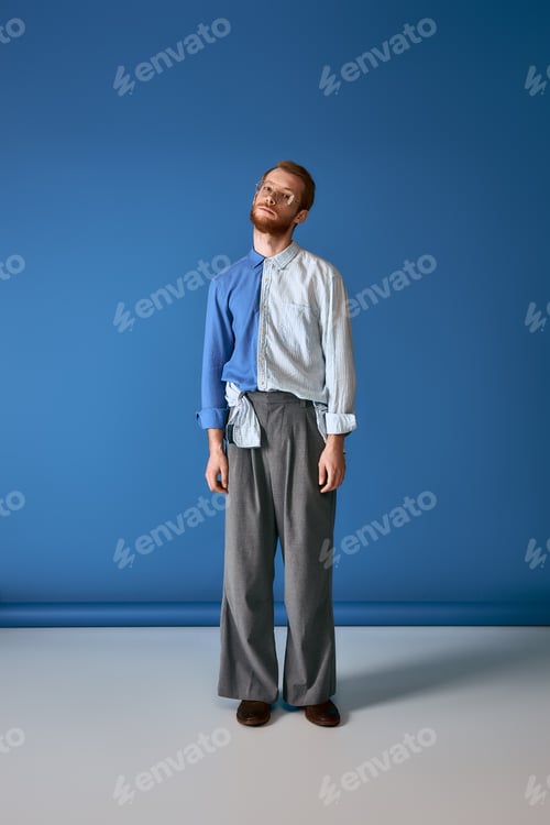 Preview: Handsome red haired man showcases stylish and artistic fashion against a vibrant blue backdrop