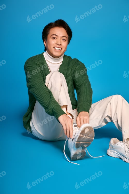 Preview: Young man displays trendy style and unique fashion choices in vibrant studio setting