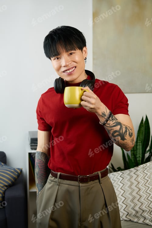 Preview: Handsome young man enjoying a moment with a yellow mug in a cozy indoor setting