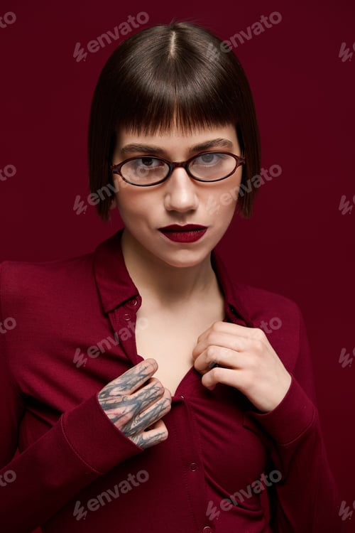 Preview: Fashionable young woman showcasing modern style in a striking burgundy setting with confidence