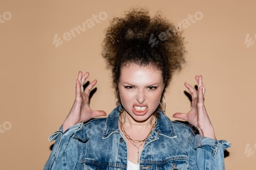 Preview: Angry model in denim jacket looking at camera on beige background