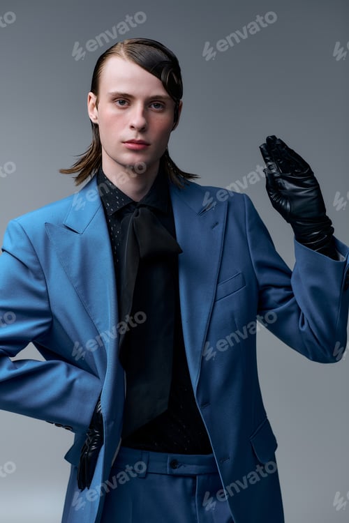 Preview: Young man showcases modern fashion with striking style in studio setting