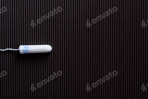 Preview: Top View of Cotton Hygienic Tampon on Black Textured Background