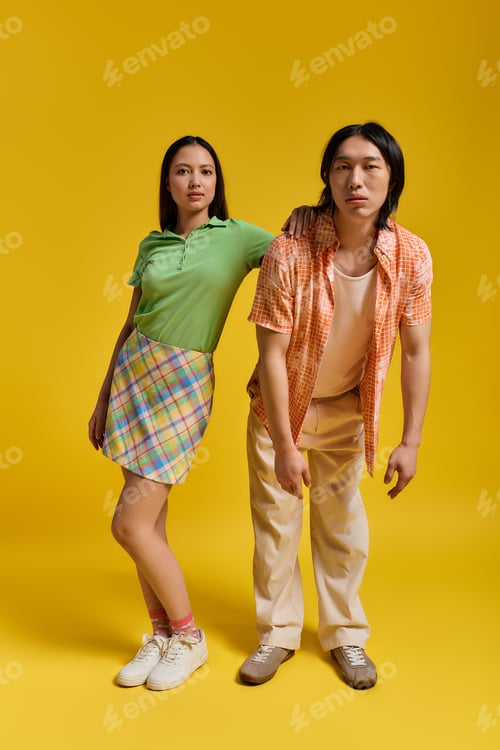 Preview: Young couple in stylish outfits sharing a playful moment against a vibrant yellow backdrop