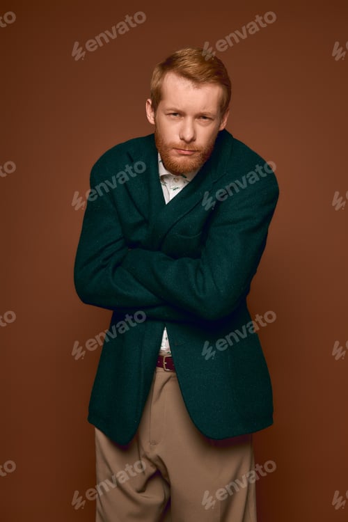 Preview: Stylish red haired man exudes charm in elegant attire against warm backdrop