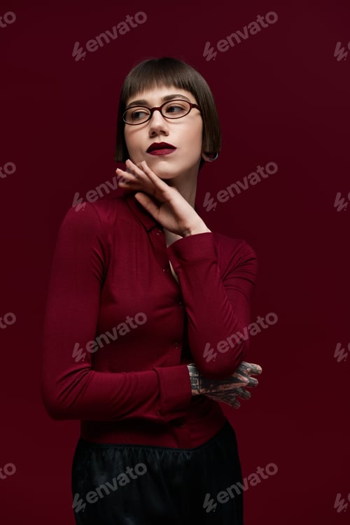 Preview: Fashionable young woman exudes confidence with stylish attire against bold red backdrop