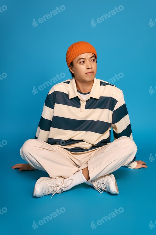 Preview: Stylish young man showcases modern fashion sense in vibrant studio setting