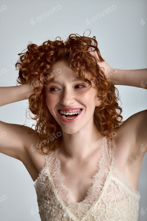 Preview: Young woman with curly hair expresses joy in stylish attire, capturing a playful moment