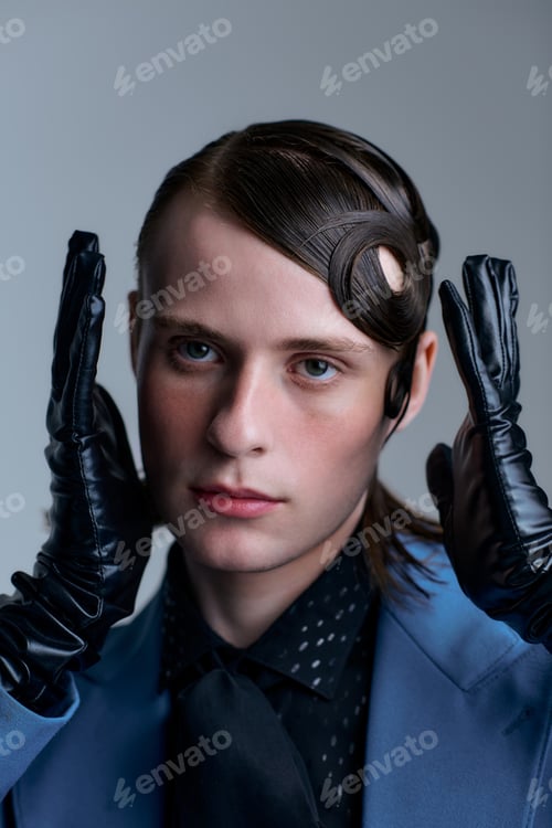 Preview: Stylish young man showcases modern fashion in a creative studio environment