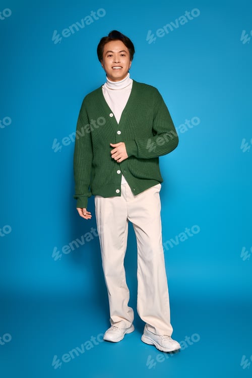 Preview: Stylish young man in a green cardigan showcasing his unique fashion sense in the studio