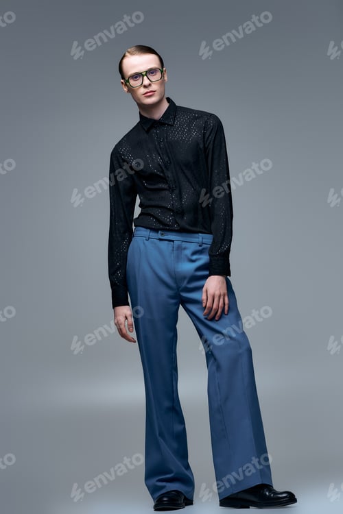 Preview: Stylish young man confidently posing in a sleek studio, showcasing modern fashion