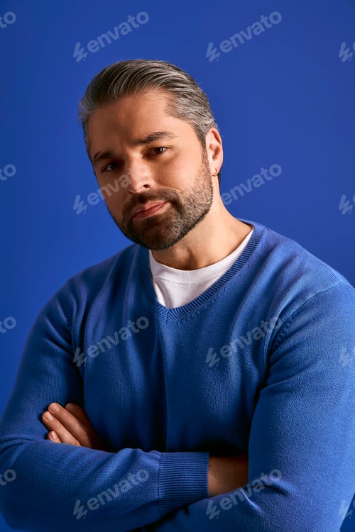 Preview: Stylish man exudes confidence against a vibrant blue backdrop in a trendy setting