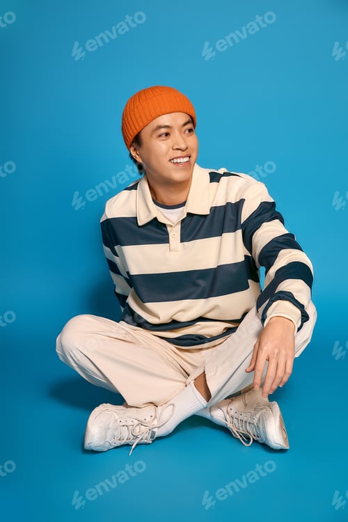 Preview: Stylish young man expresses unique fashion sense in vibrant studio setting