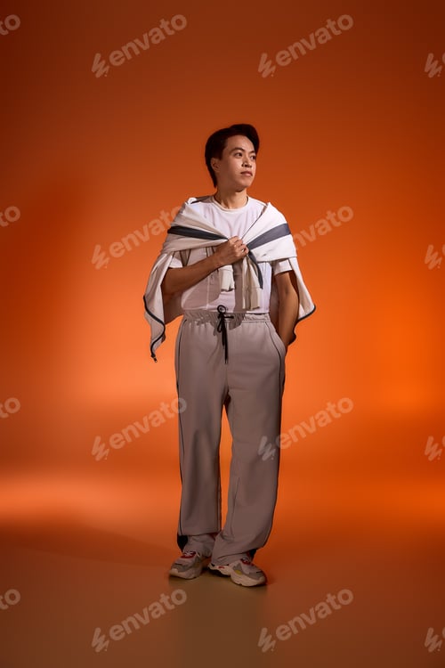 Preview: Stylish young man showcases modern fashion in vibrant studio setting with creative flair