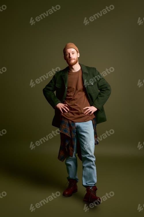 Preview: Stylish young man poses confidently with a unique fashion statement in a warm toned setting