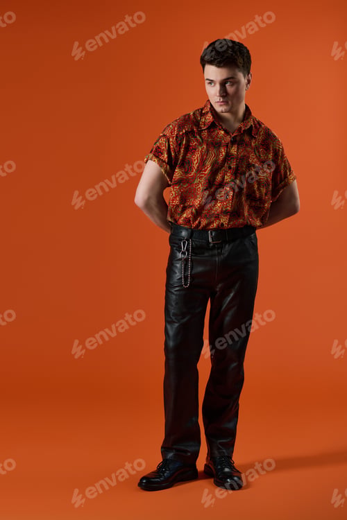 Preview: Handsome young man showcasing bold fashion with vibrant colors against an orange backdrop