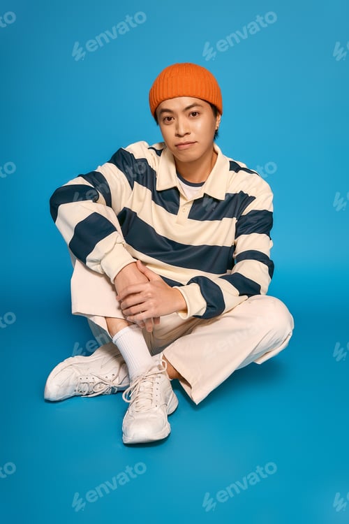 Preview: Stylish young asian man reflects modern fashion creativity in a dynamic studio setting