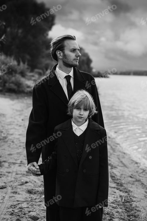 Preview: Father holding daughter hand standing near river, cloudy sky, monochrome portrait