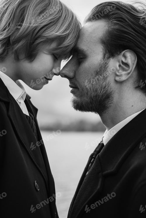 Preview: Father and daughter touching foreheads outdoors near water, monochrome portrait