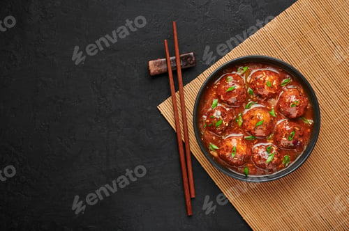 Preview: Veg Manchurian Gravy Balls in black bowl in dark slate table top. Vegetarian Indian cuisine food