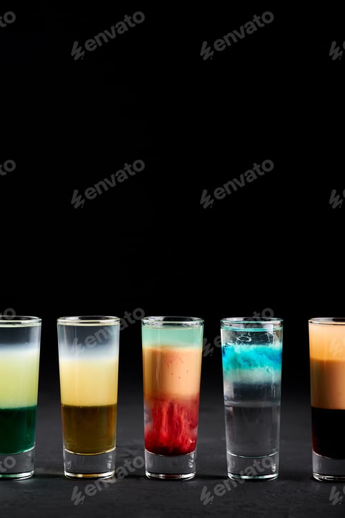 Preview: Row of shot cocktails at black slate table top. Alcoholic cocktails set. Copy space