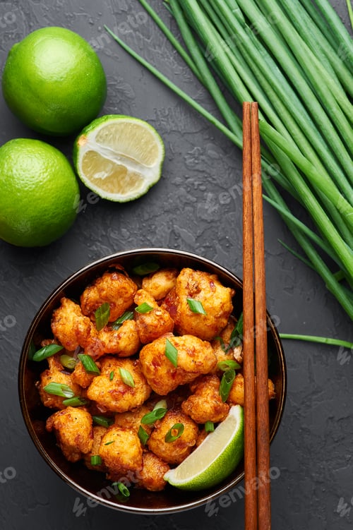 Preview: Gobi Manchurian in bowl at black concrete background. Indian Chinese cuisine vegan cauliflower dish