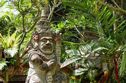 Preview: A Balinese religious statue among the lush tropical garden plants and trees