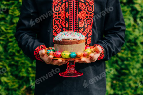 Preview: Traditional Slavic embroidered shirt and Easter bread in man's hands outdoors, spring holiday