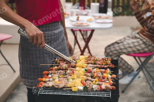 Preview: A man grilling pork and barbecue in dinner party. Food, people and family time concept.