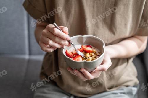 Preview: Healthy breakfast with yogurt, granola and fresh strawberries in a bowl, close-up hands
