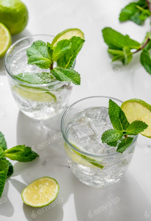Vorschau: Ein frischer Mojito mit Limette, Minze und Eis in Gläsern. Zitruslimonade oder Cocktail auf einem Marmortisch