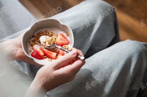 Preview: Healthy breakfast with yogurt, granola and fresh strawberries in a bowl, close-up hands