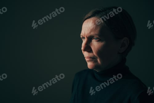 Preview: Low key image of serious mature adult brunette female, unretouched female headshot portrait