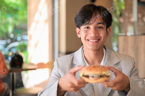 Preview: Portrait of smiling non-binary Thai Isan person offering hamburger