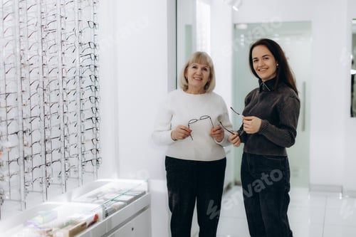 Preview: Optician assisting senior woman choosing eyeglasses