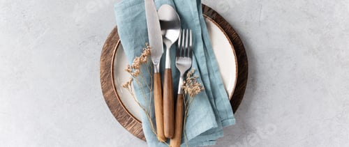 Preview: Rustic Table Setting with Blue Linen and Wooden Cutlery on Light Background