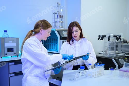 Preview: Two Female Scientists Reviewing Data on Clipboard in Modern Research Laboratory