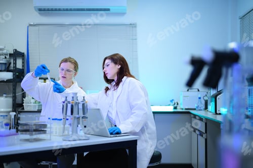 Preview: Two Female Scientists Collaborating in Modern Research Laboratory with Equipment and Laptop