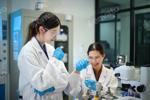 Preview: Two Asian Female Scientists Collaborating in Laboratory, Conducting Experiment with Glass Beaker and