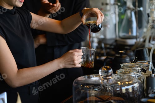 Preview: Barista Pouring Freshly Brewed Coffee into Glass Measuring Cup at Specialty Coffee Bar