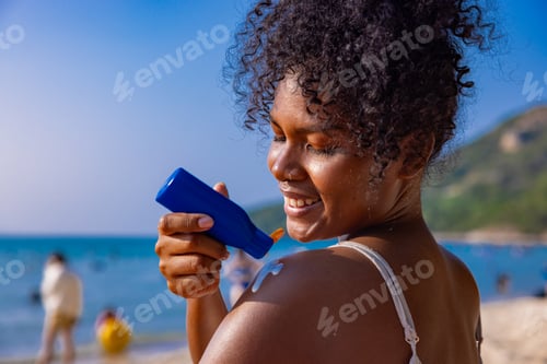 Preview: Woman Applying Sunscreen on Shoulder at Beach