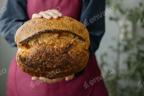 Preview: yeast-free sourdough bread. a beautiful European woman baker holds bread in her hands