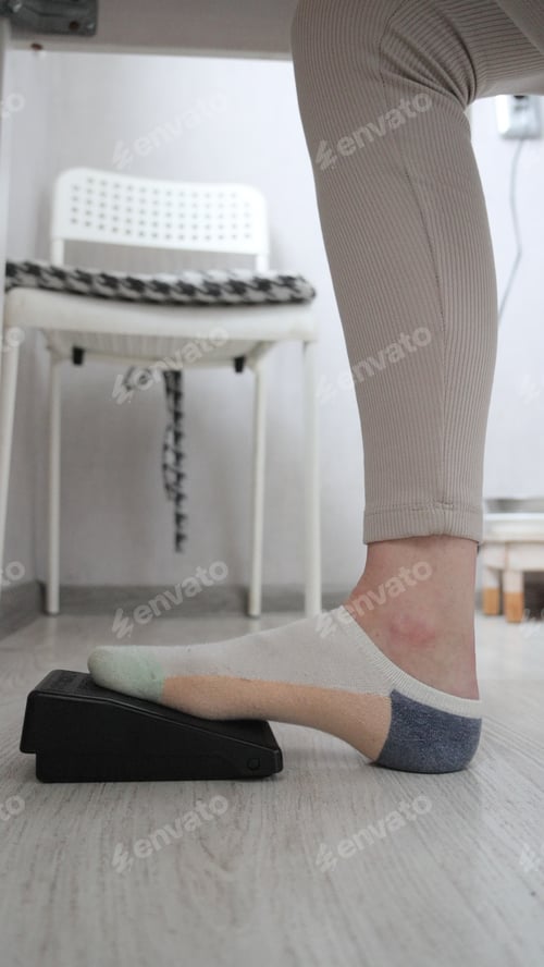 Preview: Woman's Foot Presses Pedal of Sewing Machine Under the Table. Person is Seamstress.