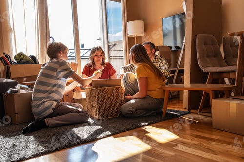 Preview: A family is moving into a new apartment, unpacking boxes together in the living room.