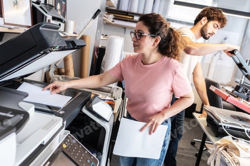 Preview: A print shop worker prepares a job on a digital color printer, checking settings and print files bef